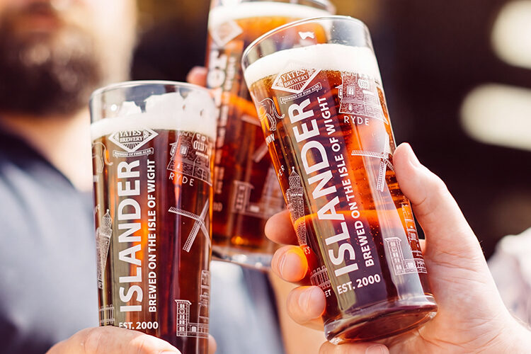 People clicking pint glasses of Islander brewed at Yates' Brewery on the Isle of Wight